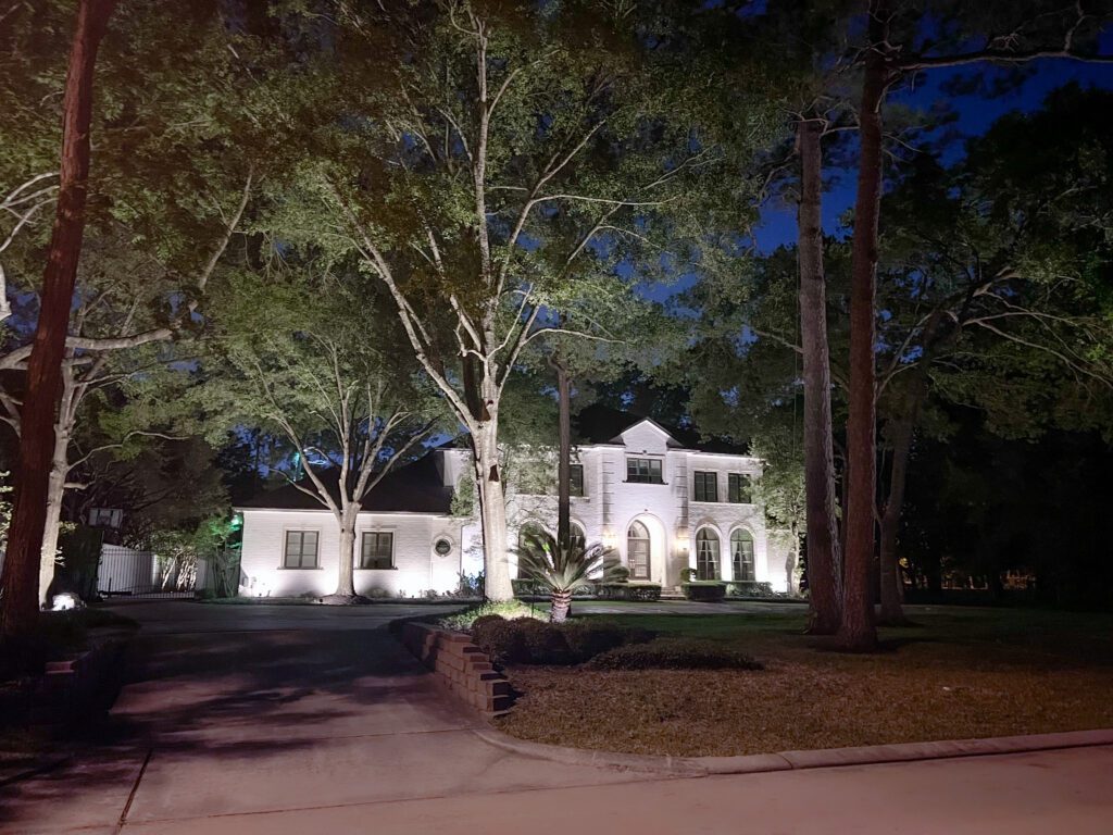 A gorgeous white house lit up by outdoor lighting. 