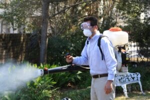 man misting bushes to get rid of mosquitos