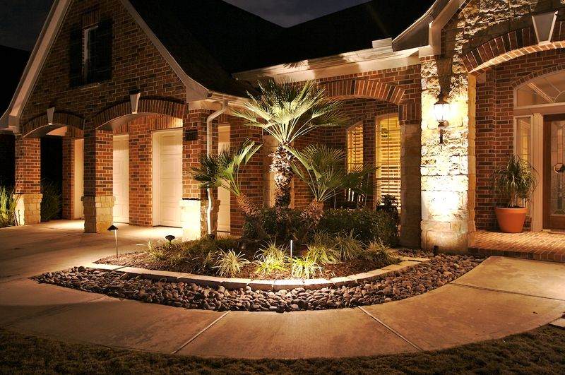 flower bed in front of a house with landscape lighting