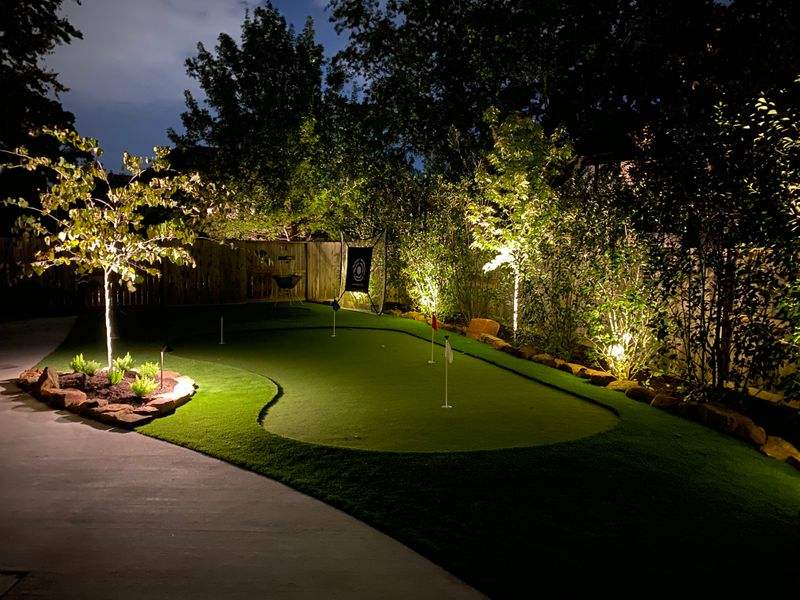mini putting green at night surrounded by outdoor lighting